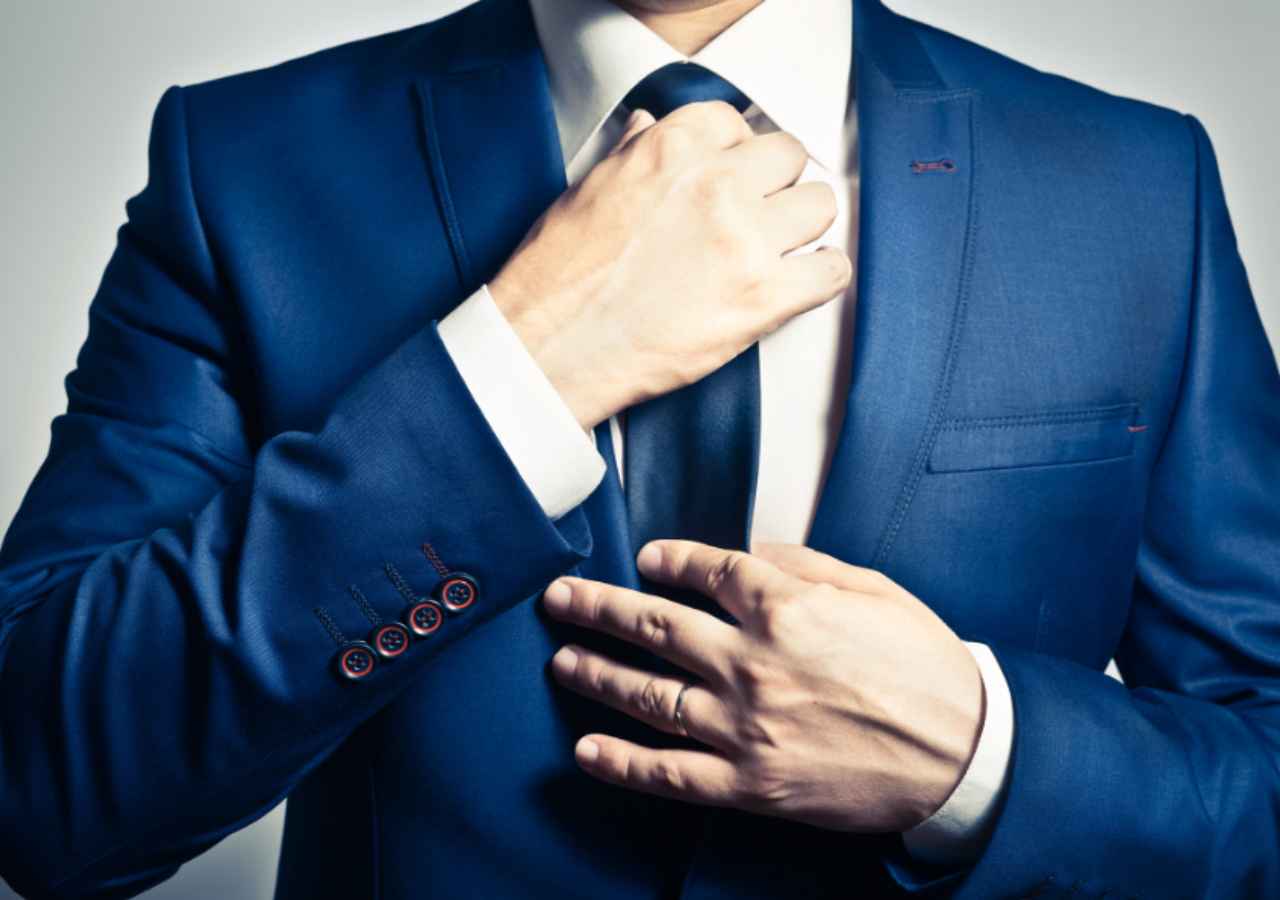 Man adjusting blue suit tie